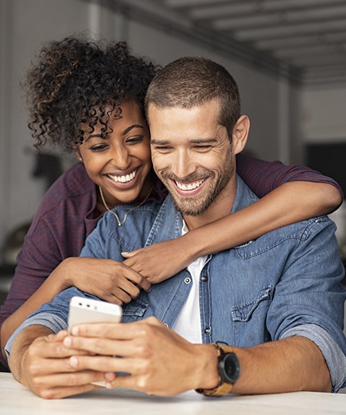 Young couple using their cell phone while smiling